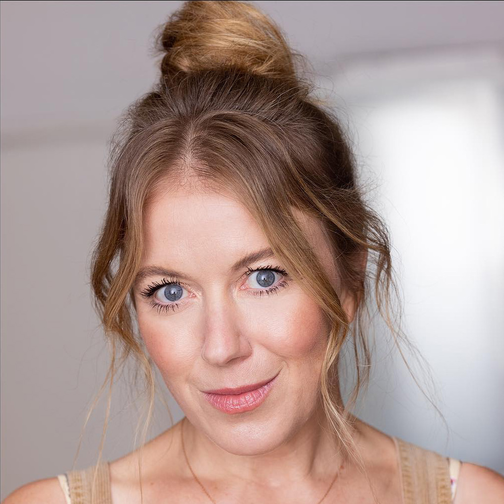 A headshot of Kate Hollinshead with her hair in a messy bun.